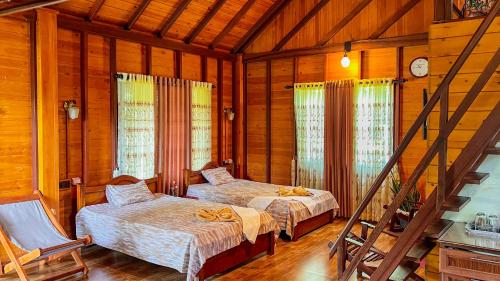 a bedroom with two beds in a wooden house at Kaba Saradiel Cabin in Mawanella