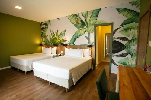 a bedroom with two beds and a mural of leaves at Tauá Hotel & Convention Caeté in Roças Novas