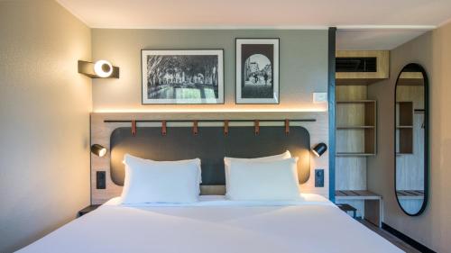a bedroom with a large bed with white pillows at Campanile NATURE - Martigues in Martigues