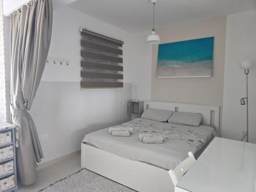 a white bedroom with a bed with two towels on it at Caesar Resort & Spa Luxury Apartments in Iskele