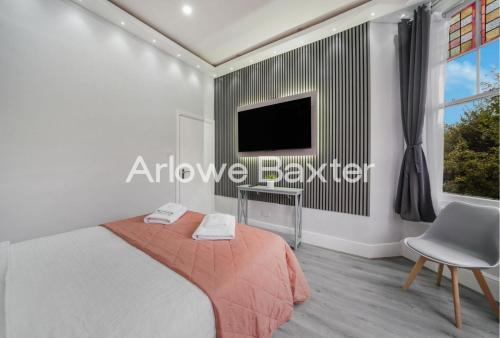 a bedroom with a bed and a tv on a wall at Hackney Deluxe Rooms in London