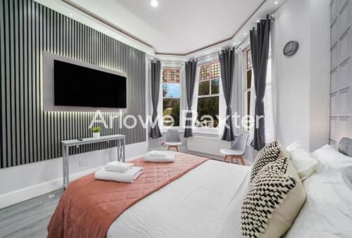 a bedroom with a large bed with a tv on the wall at Hackney Deluxe Rooms in London