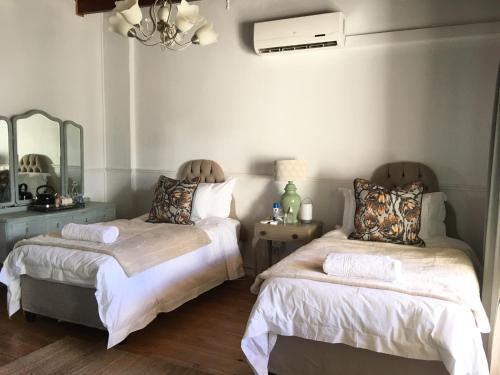 a bedroom with two beds and a mirror at Klaarstroom Hotel in Klaarstroom