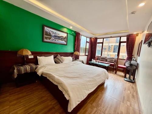 a bedroom with a green wall and a large bed at Khách Sạn Nguyễn Hùng in Sapa