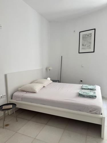 a white bedroom with a large bed and a chair at Ancient Wall House in Kampos Paros