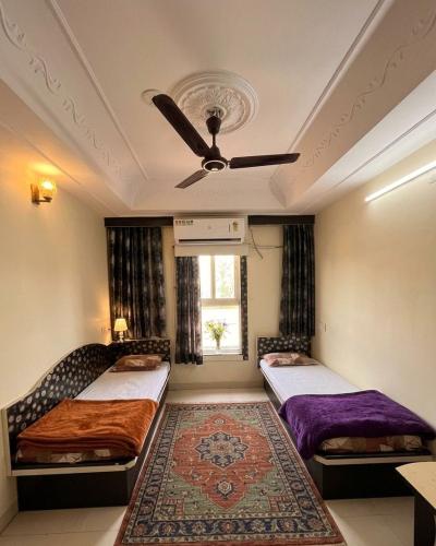 a bedroom with two beds and a ceiling fan at Hotel amrit in Indore