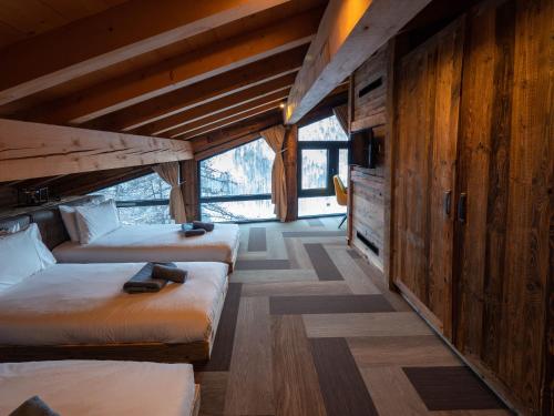two beds in a room with wooden walls at Chalet Caribou in Isola