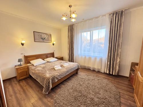 a bedroom with a bed and a large window at Квітка Закарпаття in Polyana