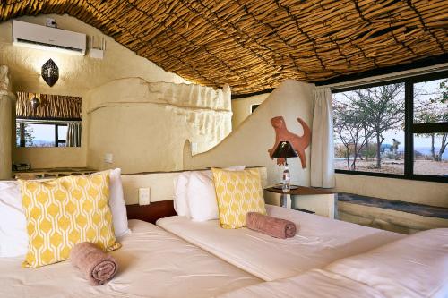 a bedroom with a large bed with yellow and white pillows at Ugab Terrace Lodge in Fingerklippe 