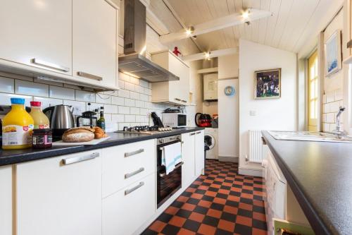 a kitchen with white cabinets and a checkered floor at Sunshine Villa Broadstairs sleeps 8 close to beach in Broadstairs