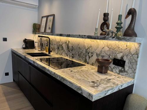 a kitchen with a marble counter top and a sink at Casiola - Design apartment with sea views in Knokke-Heist