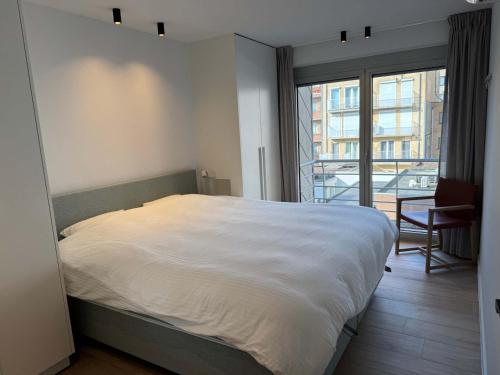 a bedroom with a large bed and a large window at Casiola - Design apartment with sea views in Knokke-Heist