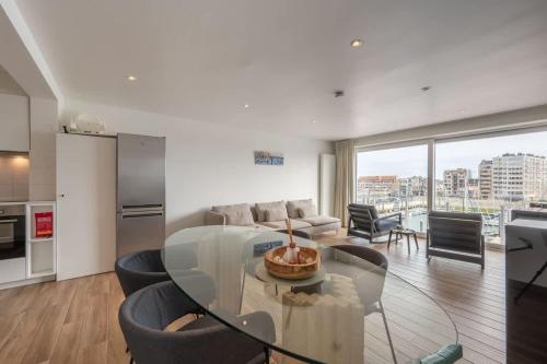 a kitchen and living room with a glass table and chairs at 2-slaapkamer appartement met zicht op de Haven in Blankenberge