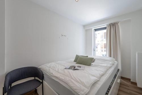 a white bedroom with a bed and a chair at 2-slaapkamer appartement met zicht op de Haven in Blankenberge