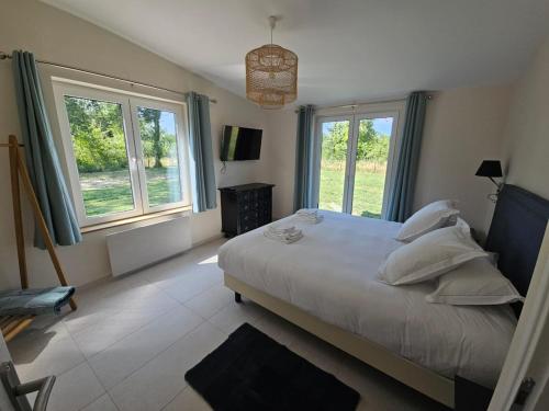 a bedroom with a large bed and two windows at Gîtes Prestige LETENDART in Saint-Quentin-en-Tourmont