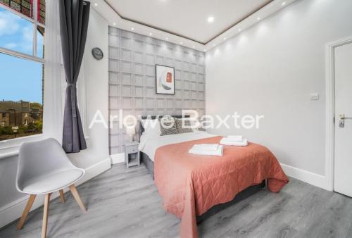 a bedroom with a bed and a chair and a window at Hackney Deluxe Rooms in London
