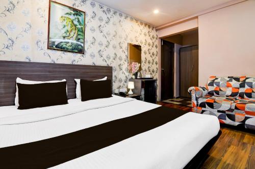 a bedroom with a large bed and a chair at Super Collection O Circus Avenue Road Formerly Hotel Rockstar in Kolkata
