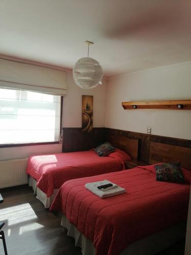 two beds in a room with red sheets at Hotel Bello, Andrés Bello 1166 in Temuco