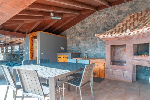a dining room with a table and chairs and a fireplace at Camara De Lobos Lux Villa in Câmara de Lobos