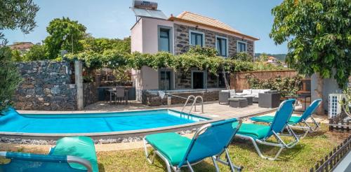 a villa with a swimming pool in front of a house at Madeirense Villa in Santa Cruz in Santa Cruz