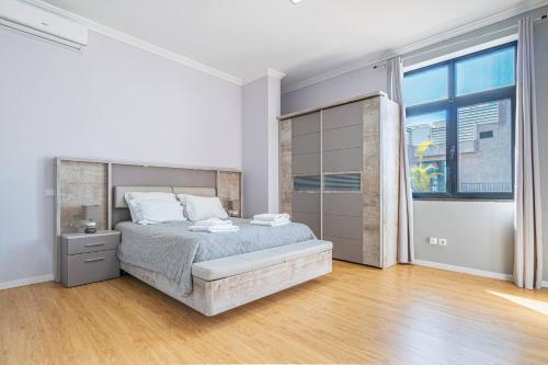 a white bedroom with a bed and a large window at Old Town T1 Apartment in Funchal