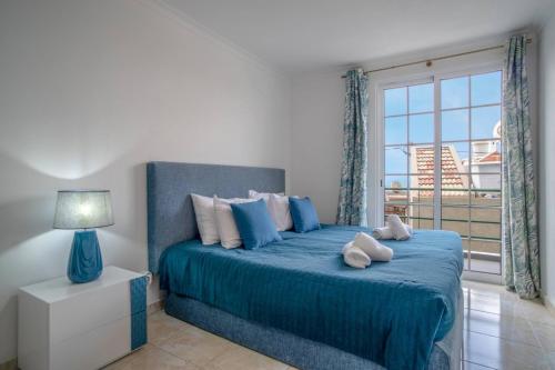 a bedroom with a blue bed with a large window at Villa Alegra Paul do Mar in Paul do Mar