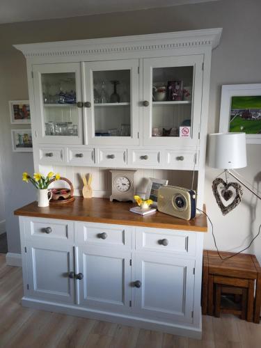 a large white cabinet with a table in a room at Rose Meadow Cottage in Liscannor