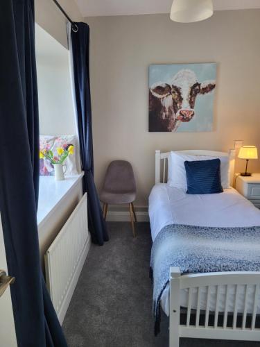 a bedroom with a bed and a chair and a window at Rose Meadow Cottage in Liscannor