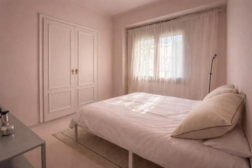 a white bedroom with a bed and a window at Winahost La Llar del Mar in San Pol de Mar