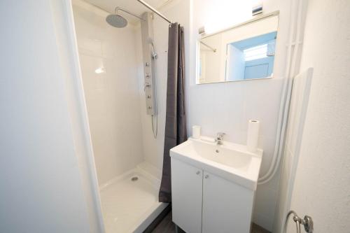 a white bathroom with a sink and a shower at AppartUnique - Chez Layette - Hypercentre & Design Moderne in Vichy