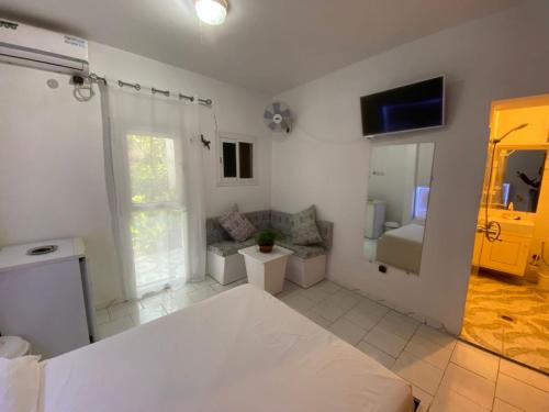 a white bedroom with a bed and a mirror at Chambre double meublée in Mbour