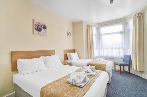 a hotel room with two beds and a window at Britannia Inn Hotel in Ilford
