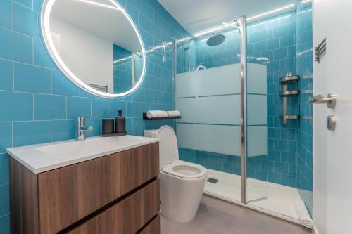 a blue tiled bathroom with a toilet and a mirror at Social Lodge Happiness Studios in Funchal