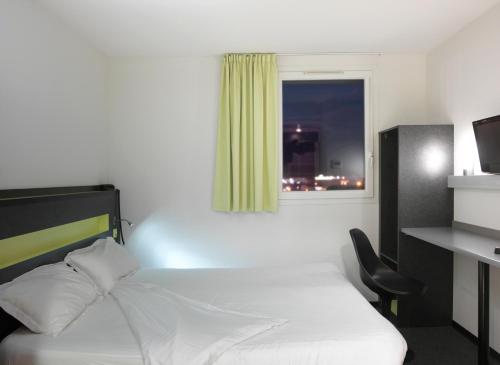 a bedroom with a bed and a desk and a window at B&B HOTEL Béthune Bruay-la-Buissière in Bruay-la-Buissiere