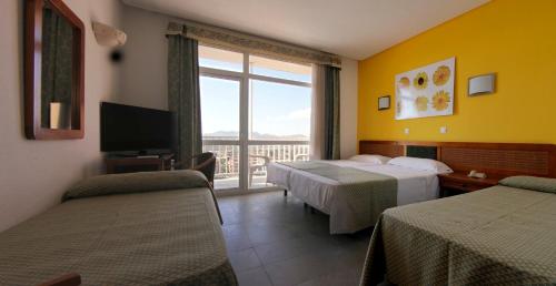a hotel room with two beds and a balcony at Hotel & Spa Entremares in La Manga del Mar Menor