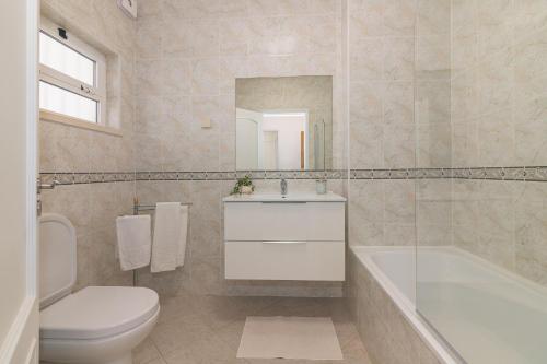 a bathroom with a sink and a tub and a toilet at Aldeamento Turistico Aldeia da Galé in Albufeira