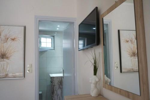 a bathroom with a mirror and a television on the wall at Pythari Summer House in Laganas