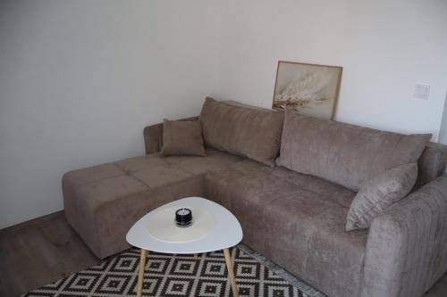a brown couch with a coffee table in a living room at Apartmani XS in Sutomore