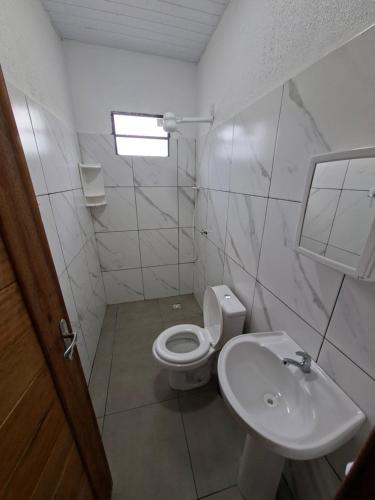 a white bathroom with a toilet and a sink at Cachoeira e Pousada dos Pássaros in Presidente Figueiredo