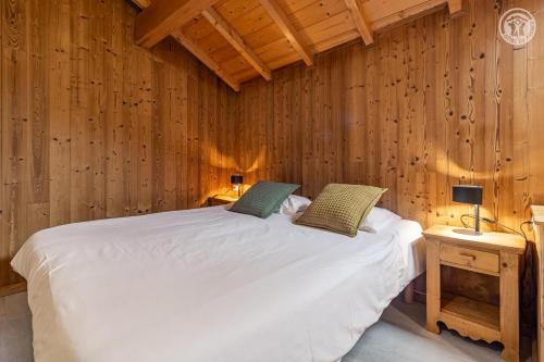 a bedroom with a white bed in a wooden wall at Gites le moulin - lanchette in La Compôte