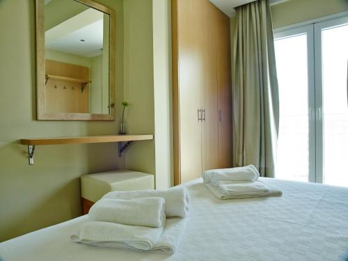 a bedroom with two towels on a bed with a mirror at Cosmos Apartments in Vasiliki