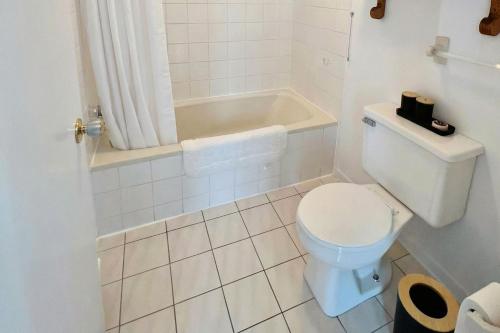 a white bathroom with a toilet and a bath tub at Motel Seal Rock in Perce