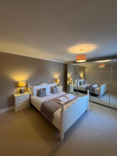 a large bedroom with a large bed and mirrors at Three Trees Cottage in Lochmaben