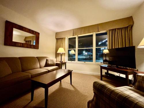 a living room with a couch and a flat screen tv at Ski in-out, Slope and Pool Views 1BR at Country Inn in Hancock