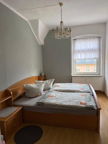 a bedroom with a bed with a chandelier and a window at Lindenstraße in Aue-Bad Schlema