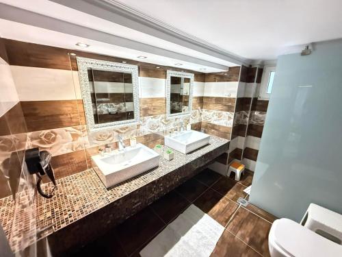 a bathroom with two sinks and two mirrors at Tropical Apartment Hanioti in Hanioti