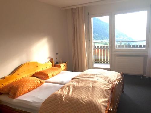 Un dormitorio con una cama y una ventana grande. en Disentiserhof C502, en Disentis