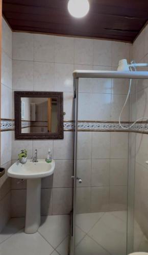 a bathroom with a sink and a shower with a mirror at Casa com área de lazer em Xerém in Duque de Caxias