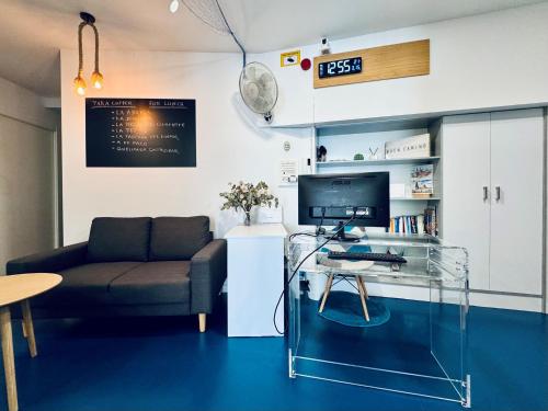 a living room with a couch and a desk with a computer at Hostel Albergue Baionamar in Baiona