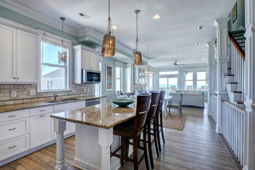 a kitchen with a island with chairs and a table at Tipsy Turtle North- Oceanfront Oasis - Pool - Dog Friendly in Surf City